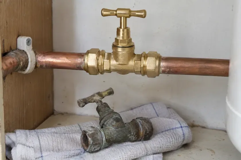 New brass main stopcock with the removed old valve beneath.